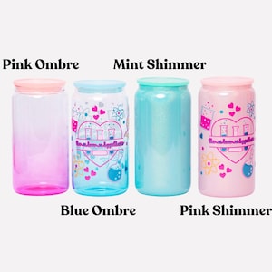 May include: Four colorful, cylindrical drinking glasses with lids. The glasses are labeled "Pink Ombre", "Blue Ombre", "Mint Shimmer", and "Pink Shimmer". The "Blue Ombre" and "Pink Shimmer" glasses have a graphic design with hearts and science-themed elements.