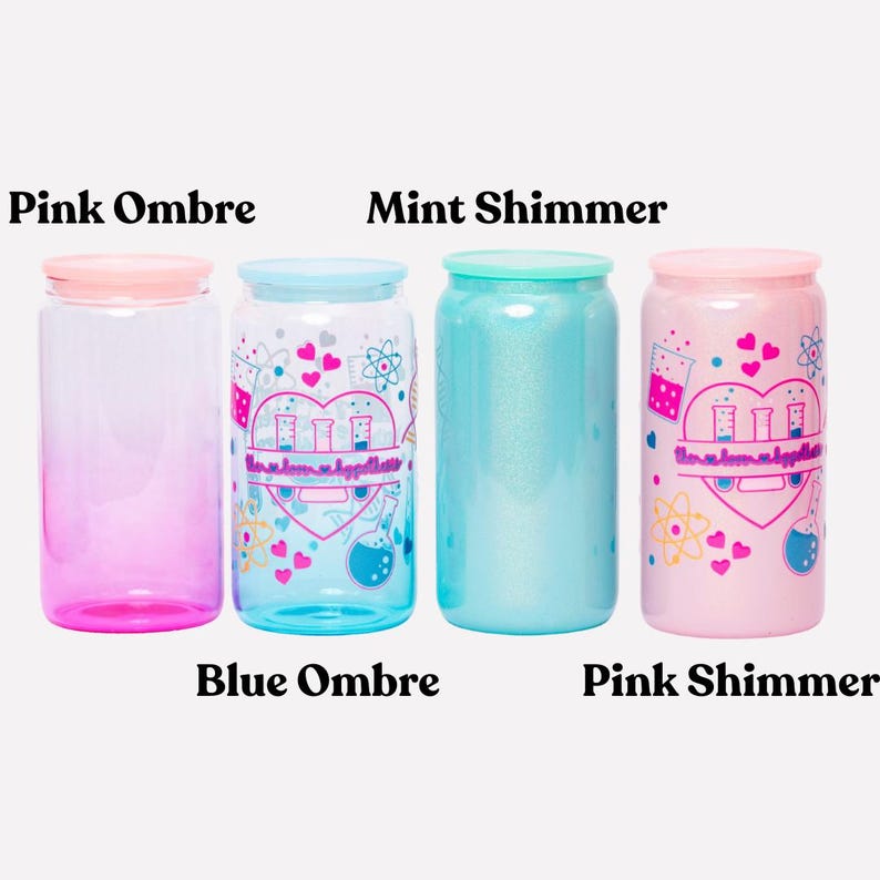May include: Four colorful, cylindrical drinking glasses with lids. The glasses are labeled "Pink Ombre", "Blue Ombre", "Mint Shimmer", and "Pink Shimmer". The "Blue Ombre" and "Pink Shimmer" glasses have a graphic design with hearts and science-themed elements.