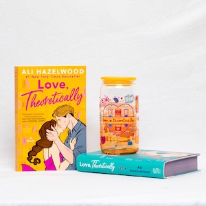 May include: A still life featuring two books and a glass jar. The book on the left has a yellow cover with the title "Love, Theoretically" and a couple kissing. The jar has a yellow lid and a graphic design. The book on the bottom is teal.