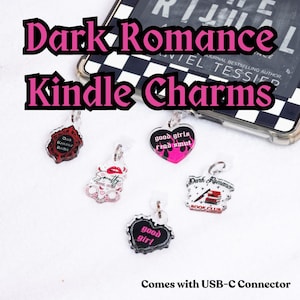 Könnte beinhalten: Eine Sammlung von Kindle-Anhängern aus Acryl mit verschiedenen Designs und Phrasen, darunter "Dark Romance Reader" und "good girls read smut". Die Anhänger sind in verschiedenen Formen und Farben gehalten, mit einem USB-C-Anschluss.
