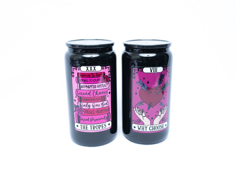 May include: Two black glass jars with pink and black labels. The jar on the left has the text "XXX" and "THE TROPES" on the label. The jar on the right has the text "VIII" and "WHY CHOOSE" on the label.
