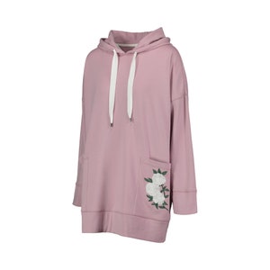 May include: A dusty rose hoodie with a drawstring hood and front pocket. The pocket features an embroidered floral design in white and green. The long-sleeved sweatshirt has a relaxed fit and is made of a soft material.