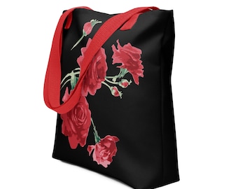 Op de afbeelding: Een zwarte tote bag met rode hengsels en een bloemenontwerp met rode rozen op een zwarte achtergrond.