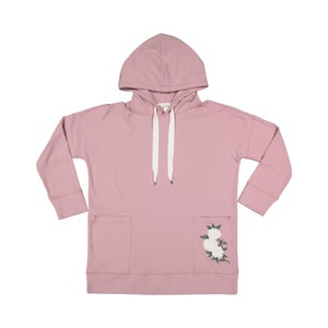 May include: A dusty rose hoodie with a hood, long sleeves, and two front pockets. White drawstrings are threaded through the hood. The lower right pocket features an embroidered floral design with white flowers and green leaves.