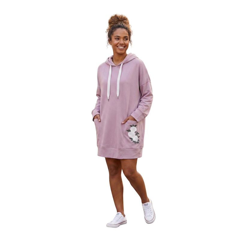 May include: A mauve hooded sweatshirt dress with a white drawstring and a front pocket featuring a floral embroidery design. The dress has long sleeves and is worn with white sneakers.