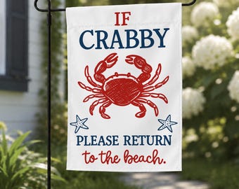 May include: A white rectangular garden flag featuring a red illustrated crab in the center, flanked by two small blue starfish. The text reads IF CRABBY in blue, and PLEASE RETURN to the beach in blue and red lettering on a white background.