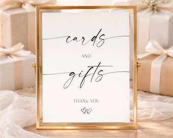 May include: A rectangular gold metal frame holding a white sign with black text that reads cards AND gifts THANK YOU with two small heart outlines below. The sign features elegant script lettering for the words cards and gifts.