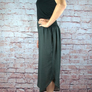 Puede incluir: Una camiseta sin mangas negra y una falda gris oscuro con un sutil estampado de puntos. La falda tiene una cintura el&aacute;stica y una abertura. La persona lleva sandalias negras.