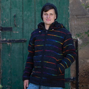 Può includere: Un maglione nero e a righe arcobaleno con chiusura a zip. Il maglione ha un cappuccio ed è realizzato in un tessuto morbido e testurizzato.