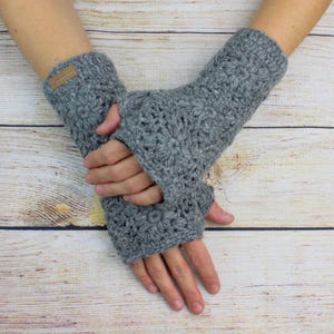 Könnte beinhalten: Graue Fingerlose Handschuhe mit einem gehäkelten Muster. Die Handschuhe sind aus einem weichen, warmen Garn gefertigt und perfekt, um Ihre Hände im Winter warm zu halten.