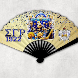 Peut inclure: Éventail décoratif avec un manche noir et une lame de ventilateur crème. L'éventail présente un sac à main bleu, un escarpin jaune, des roses jaunes et le texte "ΣΓΡ 1922". L'éventail a également un blason avec le texte "FOUNDED 1922".