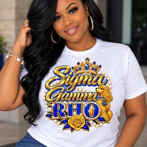 May include: A white t-shirt featuring a graphic print with the text Sigma Gamma Rho in blue and gold lettering. The design includes a gold crown, a string of pearls, a golden poodle, and a gold rose, all set against a white background.
