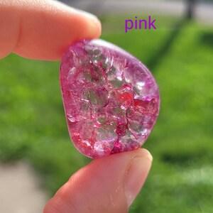 May include: A pink, translucent, heart-shaped crystal with a sparkly, iridescent finish. The crystal has a unique, cracked texture.