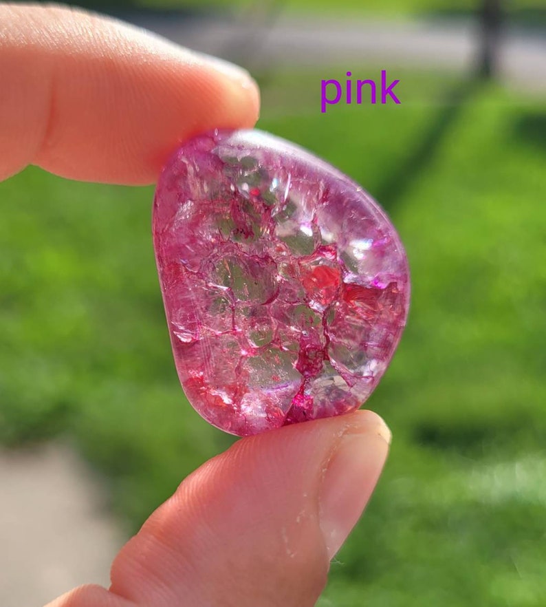 May include: A pink, translucent, heart-shaped crystal with a sparkly, iridescent finish. The crystal has a unique, cracked texture.