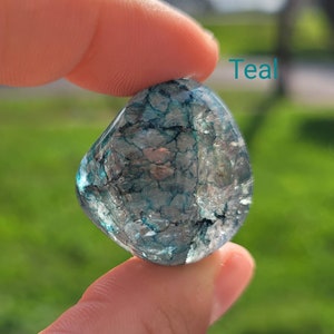May include: Teal crystal with a clear, translucent appearance and a swirling, marbled pattern of dark blue and green.