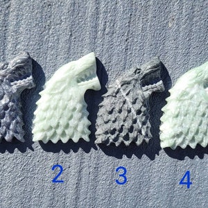 May include: Four carved wolf head figurines, two are a light green color and two are a dark gray color. The figurines are numbered 1 through 4.