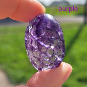 May include: A purple crystal with a unique, intricate pattern of white veins. The crystal is smooth and polished, with a slightly oval shape.