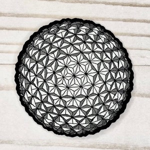 May include: A black and white embroidered patch of a geodesic dome, resembling the Spaceship Earth attraction at Epcot.