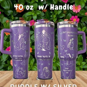 May include: A 40 oz purple tumbler with a handle, featuring silver laser-engraved illustrations of Eeyore and butterflies. The tumbler displays text including 'Eeyore', '40 oz w/ Handle', 'PURPLE W/ SILVER', and various quotes like 'never hurts to keep looking for sunshine'.