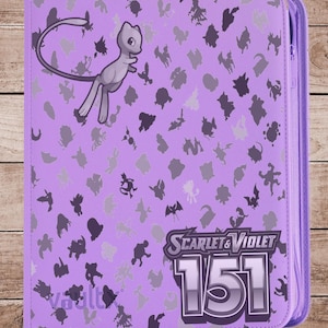 May include: A purple binder featuring a Mew graphic and various silhouettes of Pokémon characters. The binder has the text "SCARLET & VIOLET 151" and a zipper closure. The background is a wooden surface.