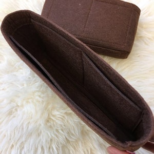 May include: Brown felt bag organiser with multiple compartments and pockets. The organiser is designed to fit inside a larger bag.