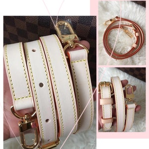 May include: A white leather strap with gold hardware and orange stitching. The strap is folded in half and has a gold clasp.