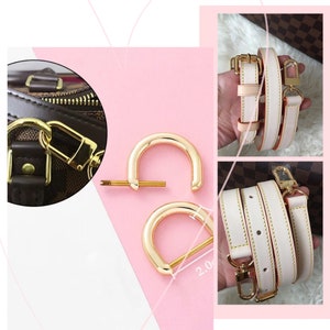 May include: Two gold-toned metal D-rings with a screw in the centre. The rings are 2.0 inches in diameter. The rings are used to attach a strap to a bag.