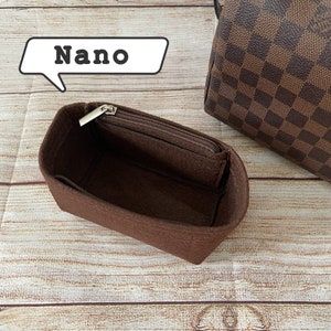 May include: A brown felt bag insert with a zipper closure. The insert is labeled "Nano" and is designed to fit inside a handbag.