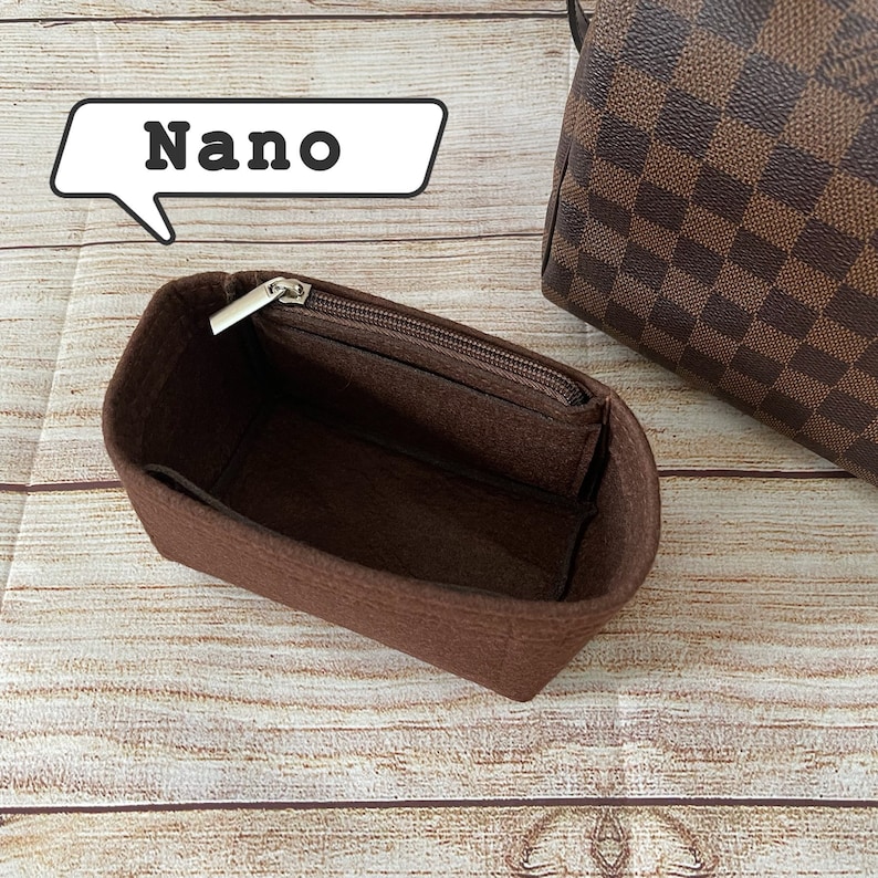 May include: A brown felt bag insert with a zipper closure. The insert is labeled "Nano" and is designed to fit inside a handbag.