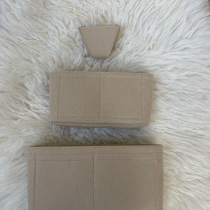 May include: Three beige felt bag organisers with different compartments. The top organiser is a small triangle shape, the middle organiser has two compartments, and the bottom organiser has three compartments.