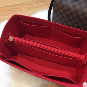 May include: Red felt bag organizer with multiple pockets and a zippered compartment. The organizer is designed to fit inside a larger bag.