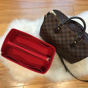 May include: Red felt bag organizer with multiple compartments and a zippered pocket. The organizer is designed to fit inside a brown and tan checkered handbag.