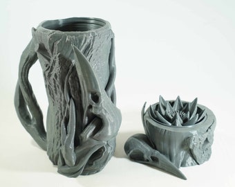 May include: A gray 3D printed mug shaped like a tree trunk with a bird skull handle and a matching lid with a flower design.