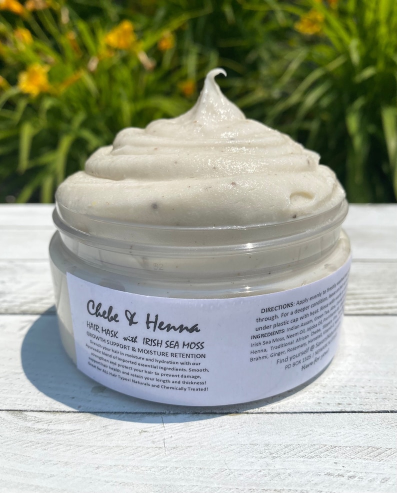 May include: A clear plastic jar filled with a thick, off-white hair mask featuring small dark specks. The white label reads Chebe & Henna Hair Mask with Irish Sea Moss, Growth Support & Moisture Retention, along with directions and ingredients.