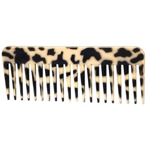 May include: A black and white patterned comb with a wide tooth design.
