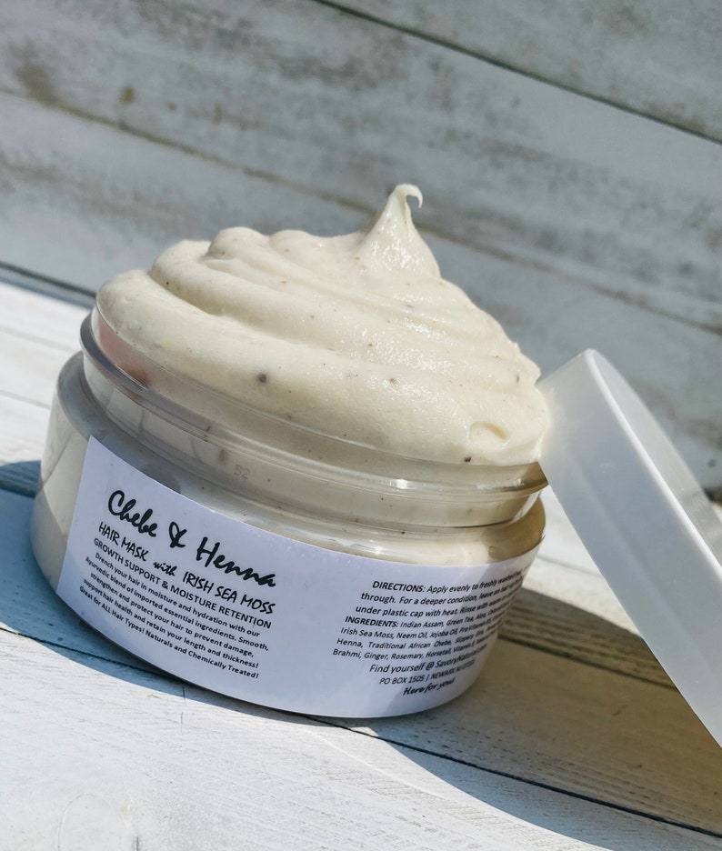 May include: A round plastic jar filled with a thick, off-white hair mask featuring small dark particles. The white label reads Chebe & Henna Hair Mask with Irish Sea Moss, Growth Support & Moisture Retention, along with directions and ingredients.