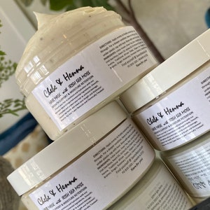 May include: Three clear plastic jars filled with a thick, off-white Chebe and Henna hair mask with Irish Sea Moss. Each jar features a white label with black text detailing directions, ingredients, and the product name in a script font.