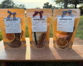 May include: Three clear bags of simmer pot ingredients, each with a different bow. The bags are labeled "Sweet Peach Pie", "Apple Pie", and "Pumpkin Pie". Each bag contains dried fruit and spices.