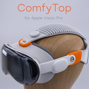 May include: A white and orange head strap for the Apple Vision Pro, called "ComfyTop". The strap is made of a soft, padded material and has adjustable straps. It is designed to provide a more comfortable fit for the Apple Vision Pro.