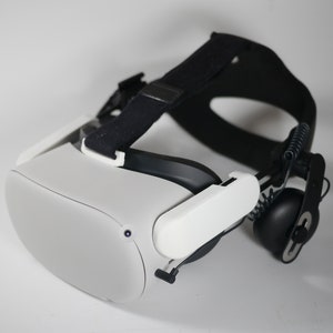 May include: A white virtual reality headset with a black strap and a black headphone attached to the side.