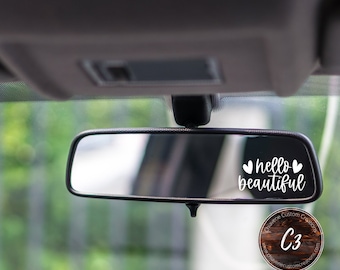 May include: A white car rearview mirror with a white vinyl decal that says "hello beautiful" with two small hearts on either side of the word "hello".