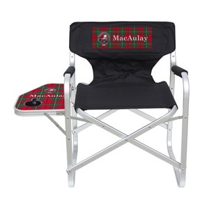 May include: A black and silver folding chair with a side table. The chair features the name "MacAulay" in white text on a red, green, and white plaid pattern. The chair has a cup holder and armrests.