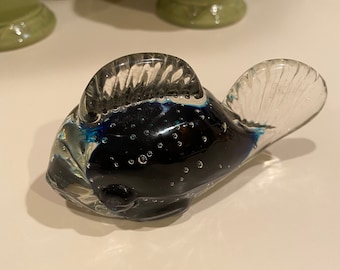 May include: A blue glass fish figurine with clear glass fins and a textured body. The fish has small air bubbles throughout the body.