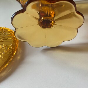 K&ouml;nnte beinhalten: Eine antike Bonbonniere aus bernsteinfarbenem Glas mit floralem Muster. Die Schale hat einen gewellten Rand und einen bl&uuml;tenf&ouml;rmigen Boden.