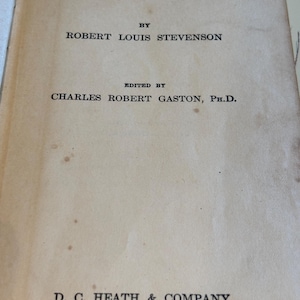 May include: The title page of the book "Treasure Island" by Robert Louis Stevenson. The text is in black font on a cream-colored page. The publisher's name, D.C. Heath & Company, and the cities Boston, New York, and Chicago are also visible.