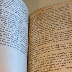 May include: Open pages of an antique book with text. The text is in English and appears to be from a novel. The pages are yellowed with age, and the book is open to a double-page spread.