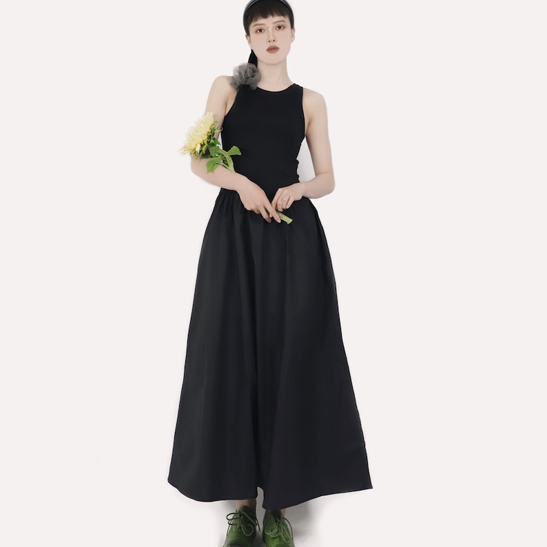May include: A black sleeveless top paired with a black maxi skirt. The skirt has a gathered waist and a flowing silhouette.