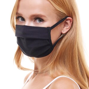 May include: A black face mask with pleats and elastic ear loops. The mask is worn by a person with long blonde hair.