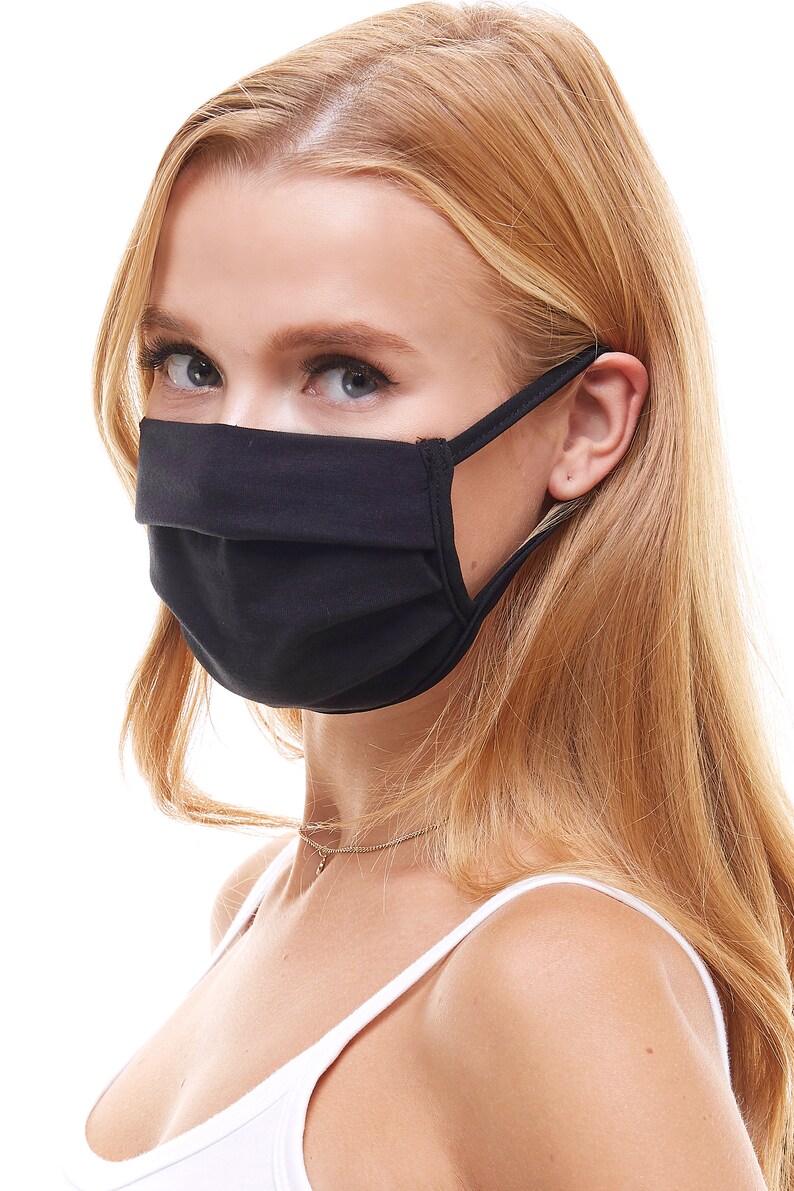 May include: A black face mask with pleats and elastic ear loops. The mask is worn by a person with long blonde hair.