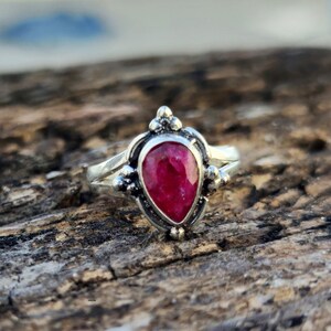 May include: A silver ring with a teardrop-shaped ruby gemstone set in a detailed silver setting.